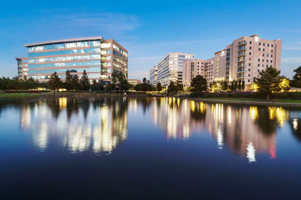 A twilight lakeview illuminating diverse buildings and trees, creating a stunning cityscape.