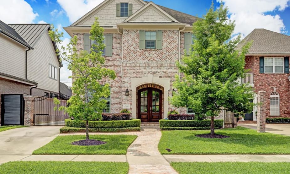 A large, two-story brick house with a black metal roof and a white trim