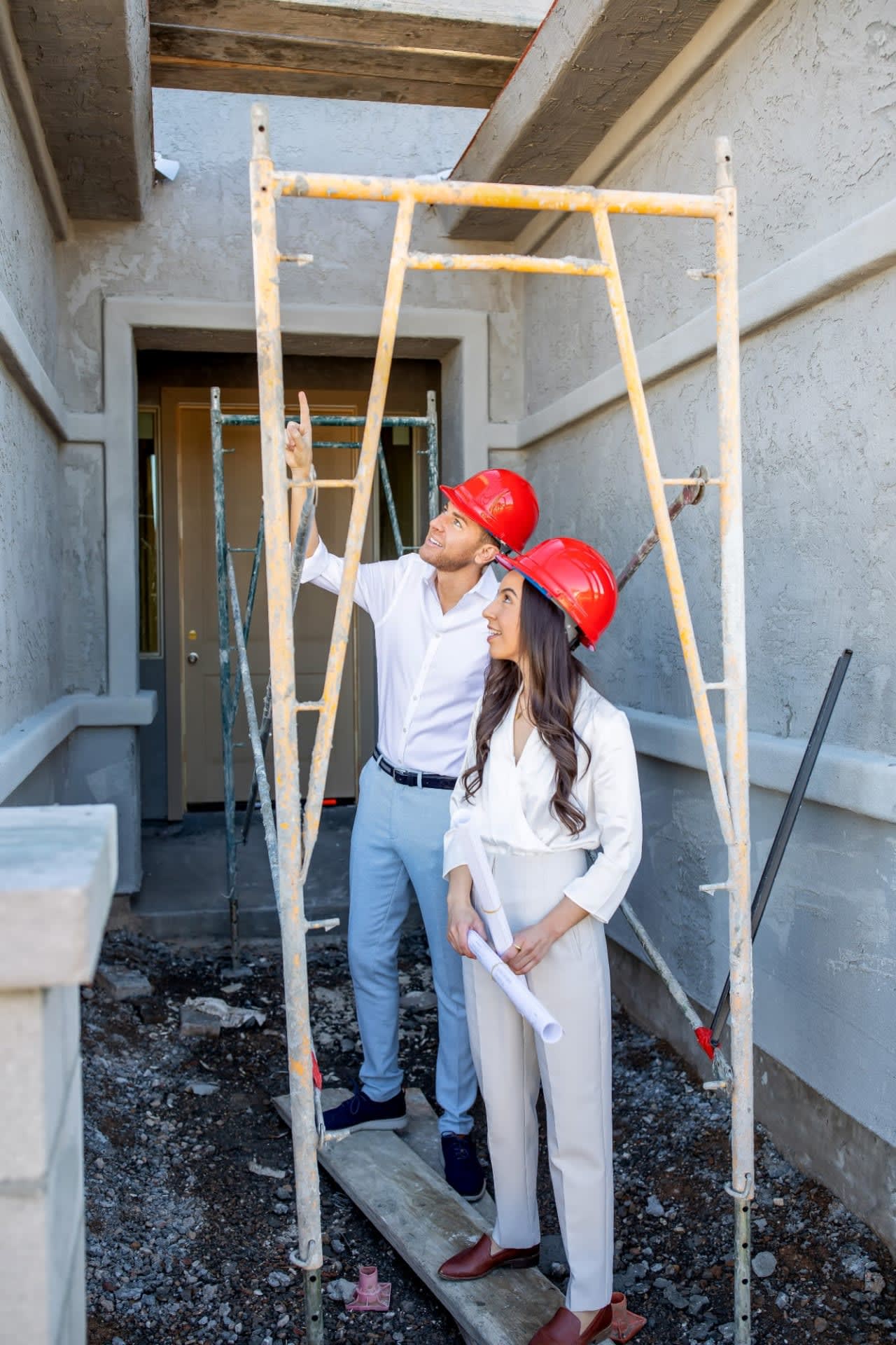 Professionals in hard hats smiling confidently at a construction site, indicating progress on a luxury real estate project.