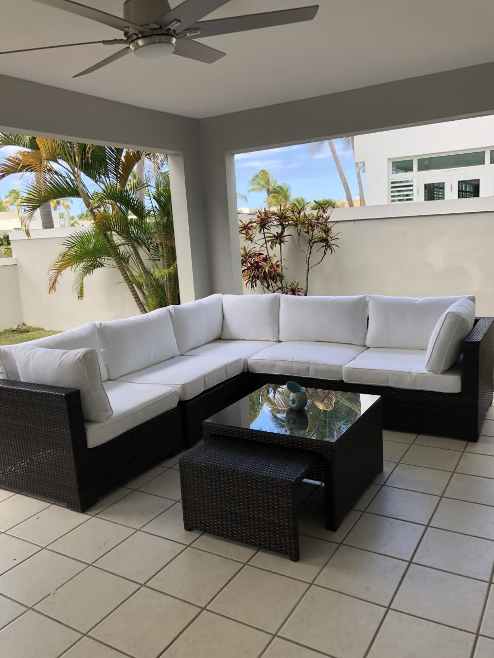 A cozy patio with a sectional couch, coffee table, and ceiling fan.