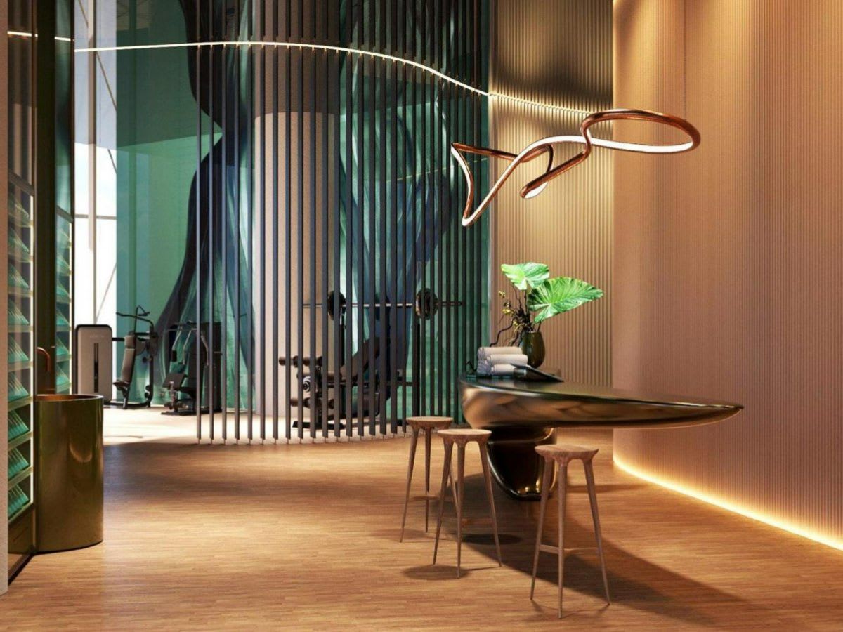 Luxury reception area with a sculptural desk and gym equipment behind a slatted divider.