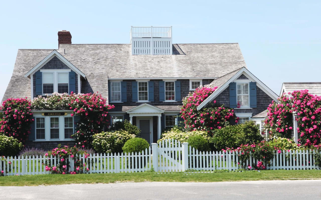 A cozy Cape Cod home with a white picket fence, representing the dream of homeownership.