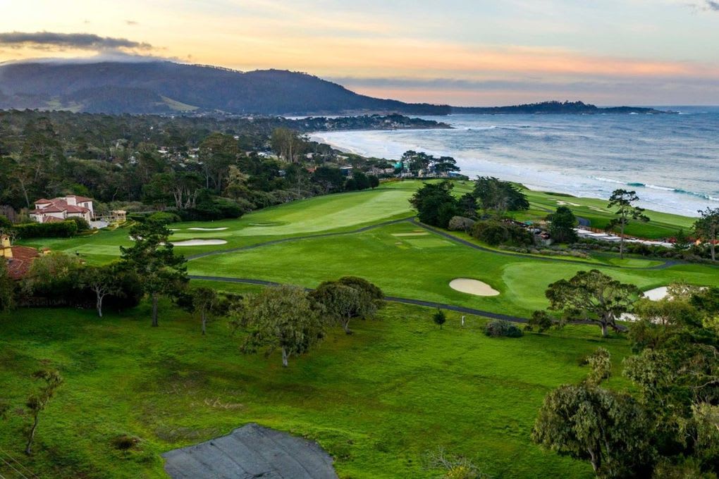 Coastal golf course with Pacific Ocean, shoreline homes, and mountains in the distance.
