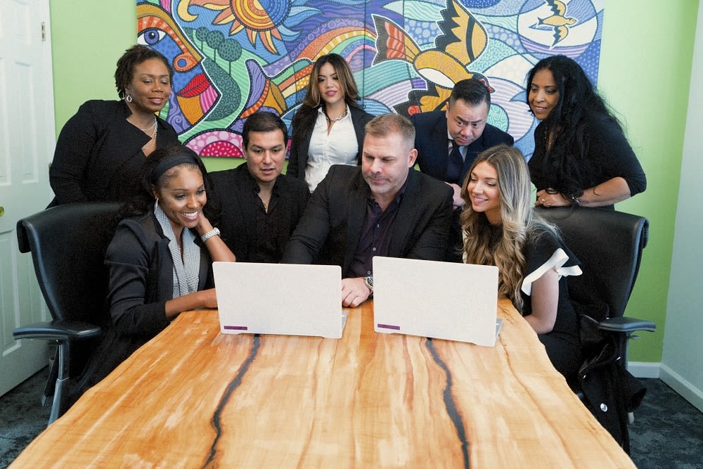 The Chaconas Team, sitting around a laptop in a conference room