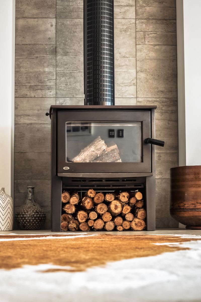 A cozy living room with a wood-burning stove in the foreground.