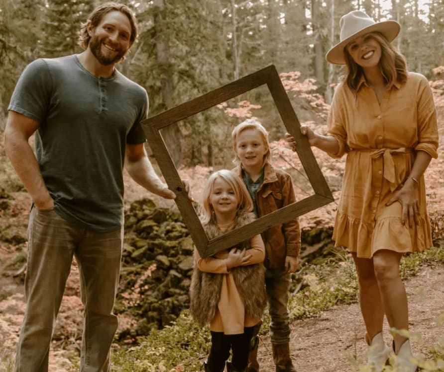 Chrissy and Brock Wood with their two children in a wooded setting.