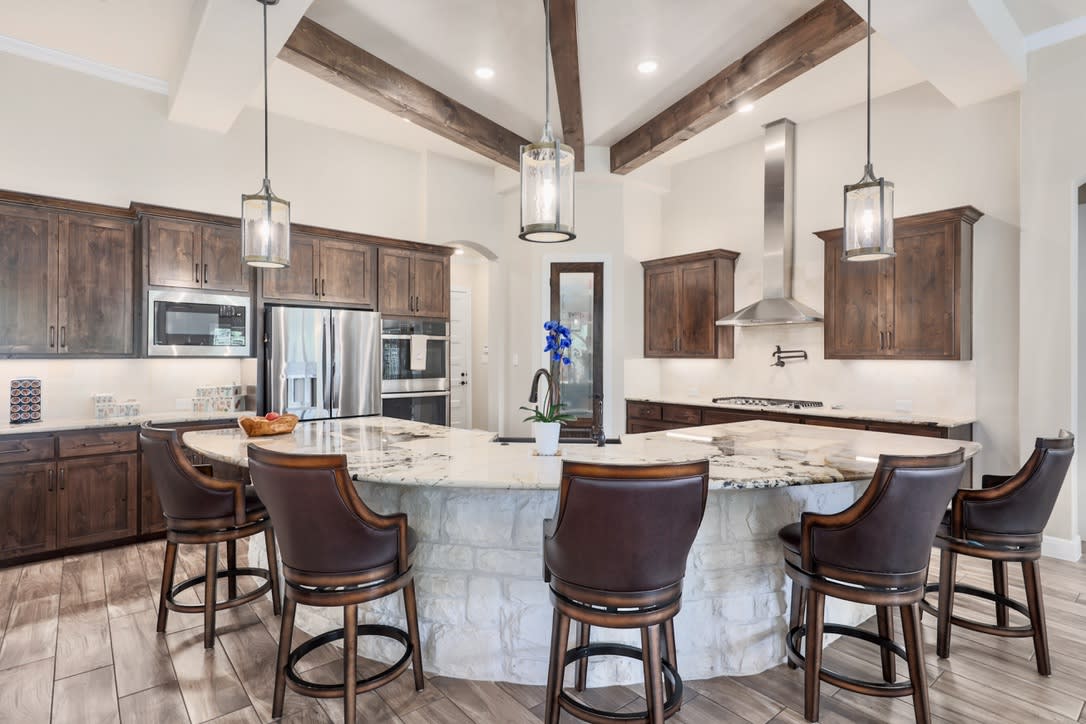 The kitchen's focal point is the upgraded expansive curved stone island, topped with translucent Roca Montana granite imported from Brazil perfect for casual dining and entertaining