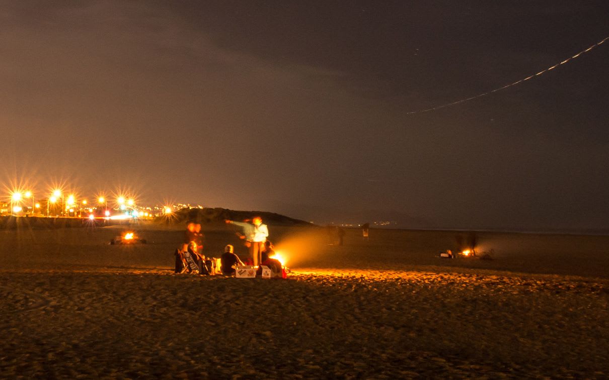 a group of people on Ocean Beach, San Francisco at night