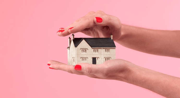 a house figurine between palms with a pink background