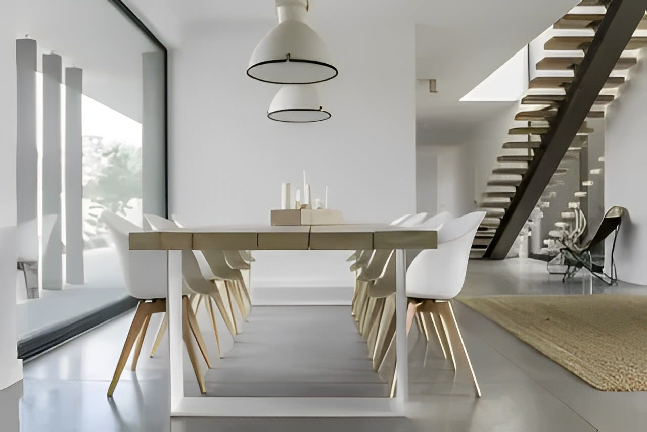 A modern dining room with a white table and white chairs