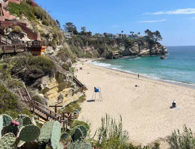 Empty beach with sandy shore, surrounded by cliffs and ocean view.