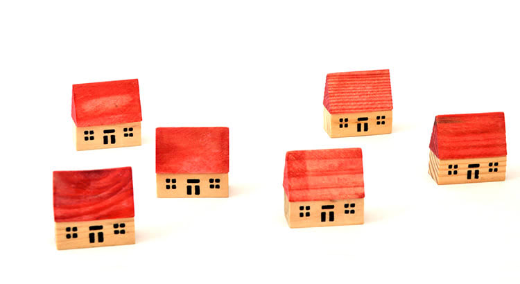 An image showing small wooden house models in red and natural wood colors, likely related to real estate or housing market information.