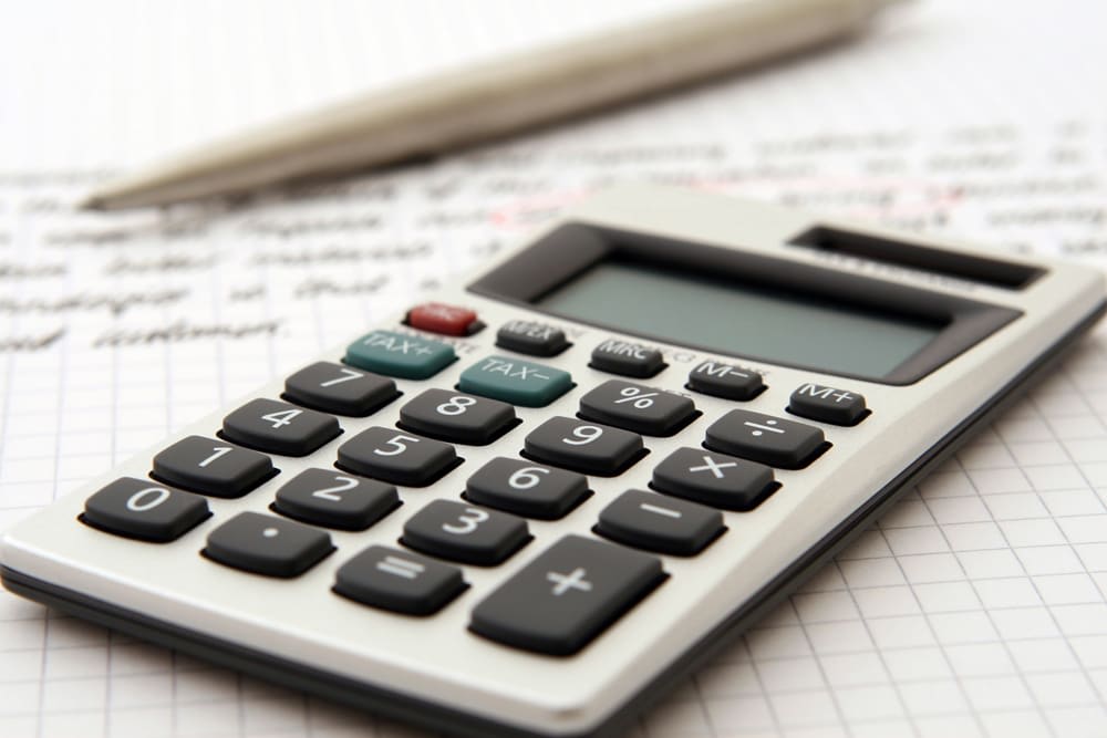 Calculator with memory and tax keys on gridded paperwork.