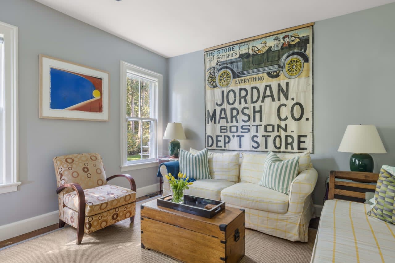 A living room with a couch and a chair, with a view of the ocean in the background, in Hampton, NY.