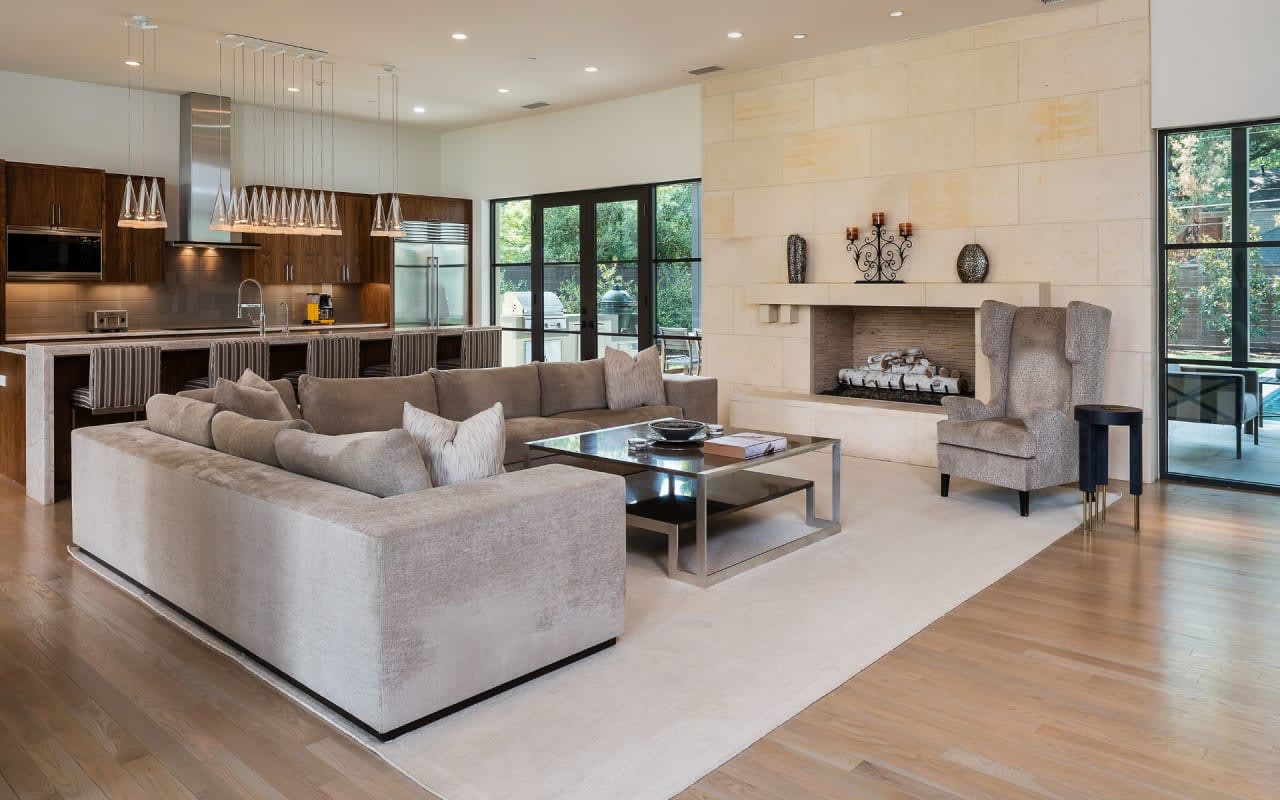 Open concept living and kitchen area highlighting an eye-catching stone fireplace at the heart of an exquisite stone wall.