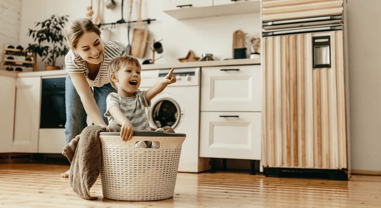 Photo of mom and son playing with laundry basket on kitchen floor