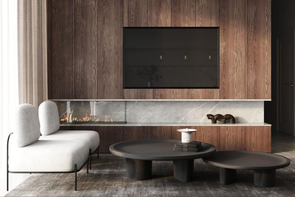 Contemporary living room with a minimalist white chair, round coffee tables, wall-mounted TV, and a sleek linear fireplace.