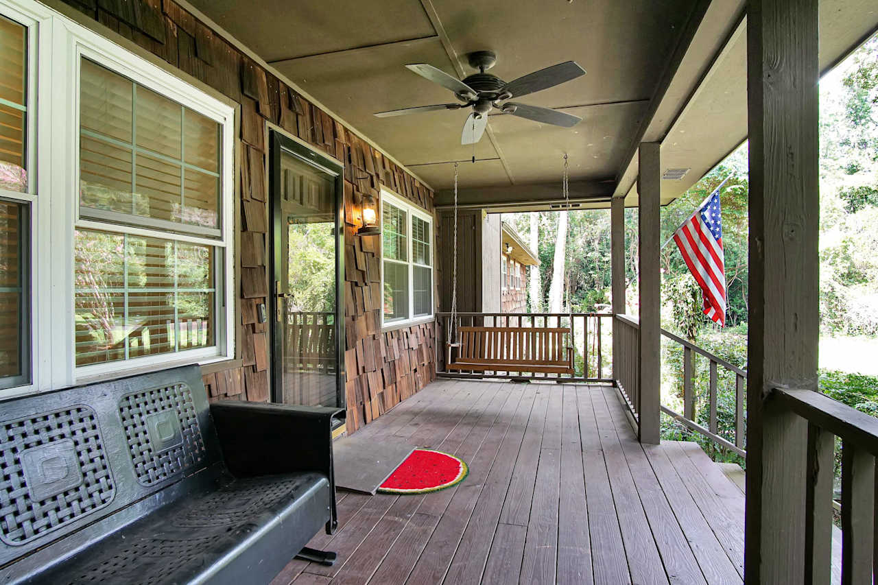 Photo of rocking chair front porch featuring a ceiling fan windows and a secondary glass door