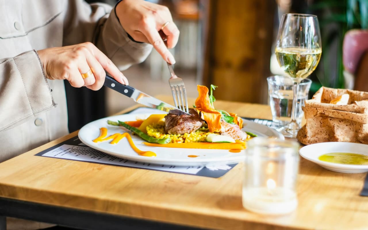 A person eating steak at a restaurant.