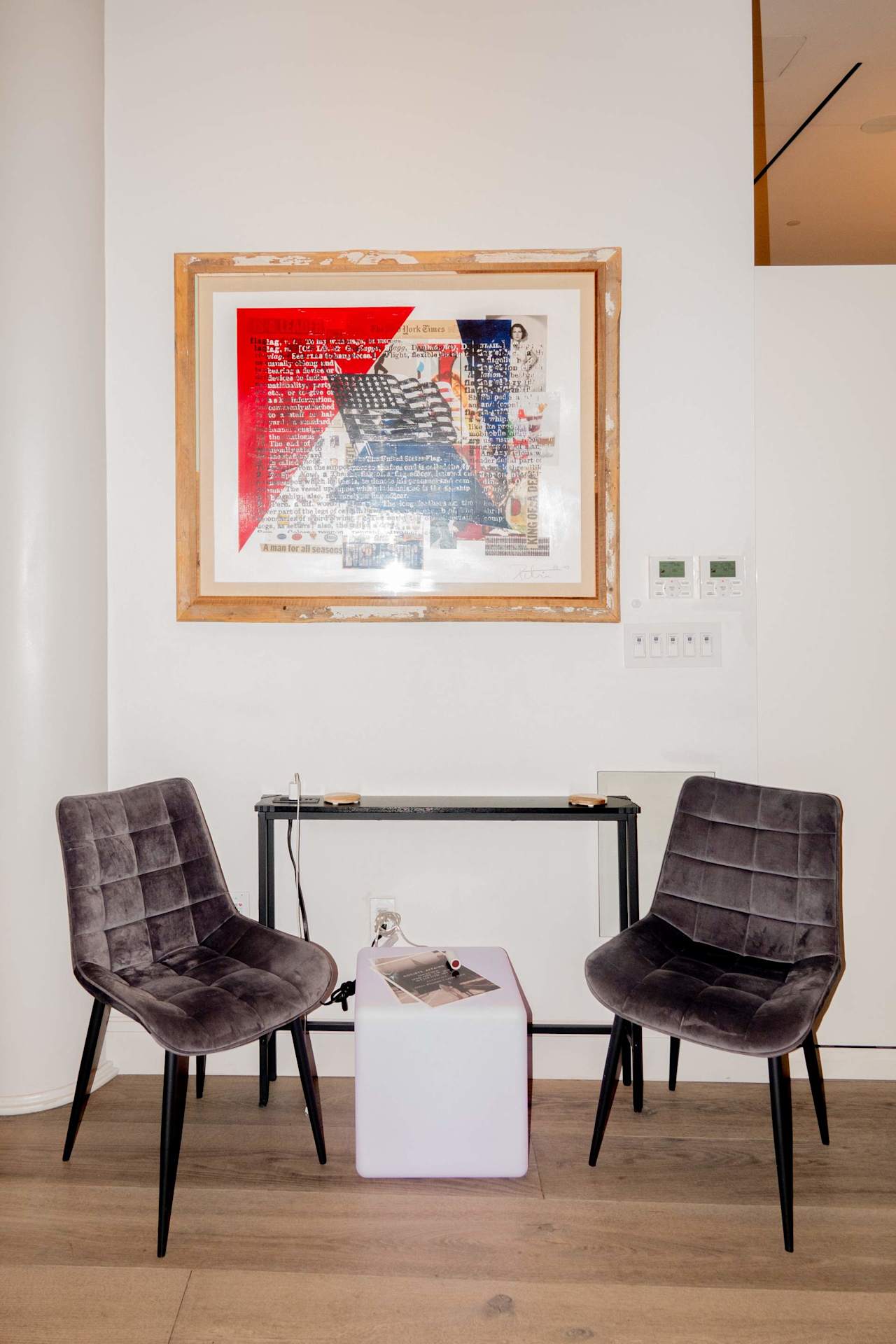 Office seating area with two dark chairs, a small table, and framed collage artwork.