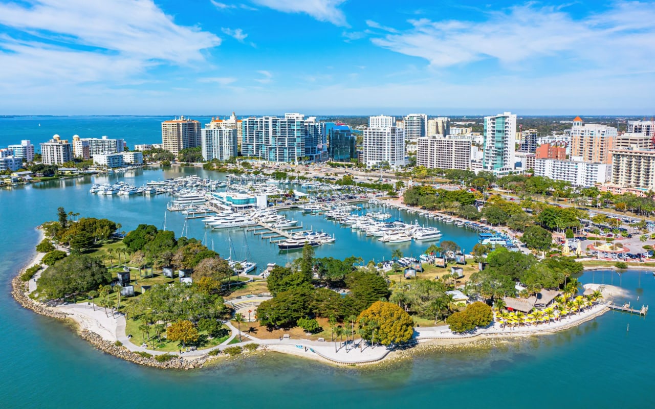 An aerial view of a marina in a city with tall buildings in the background.