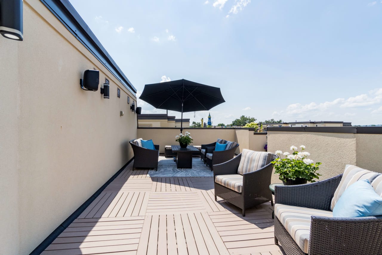 A rooftop deck with a seating area and an umbrella for shade.
