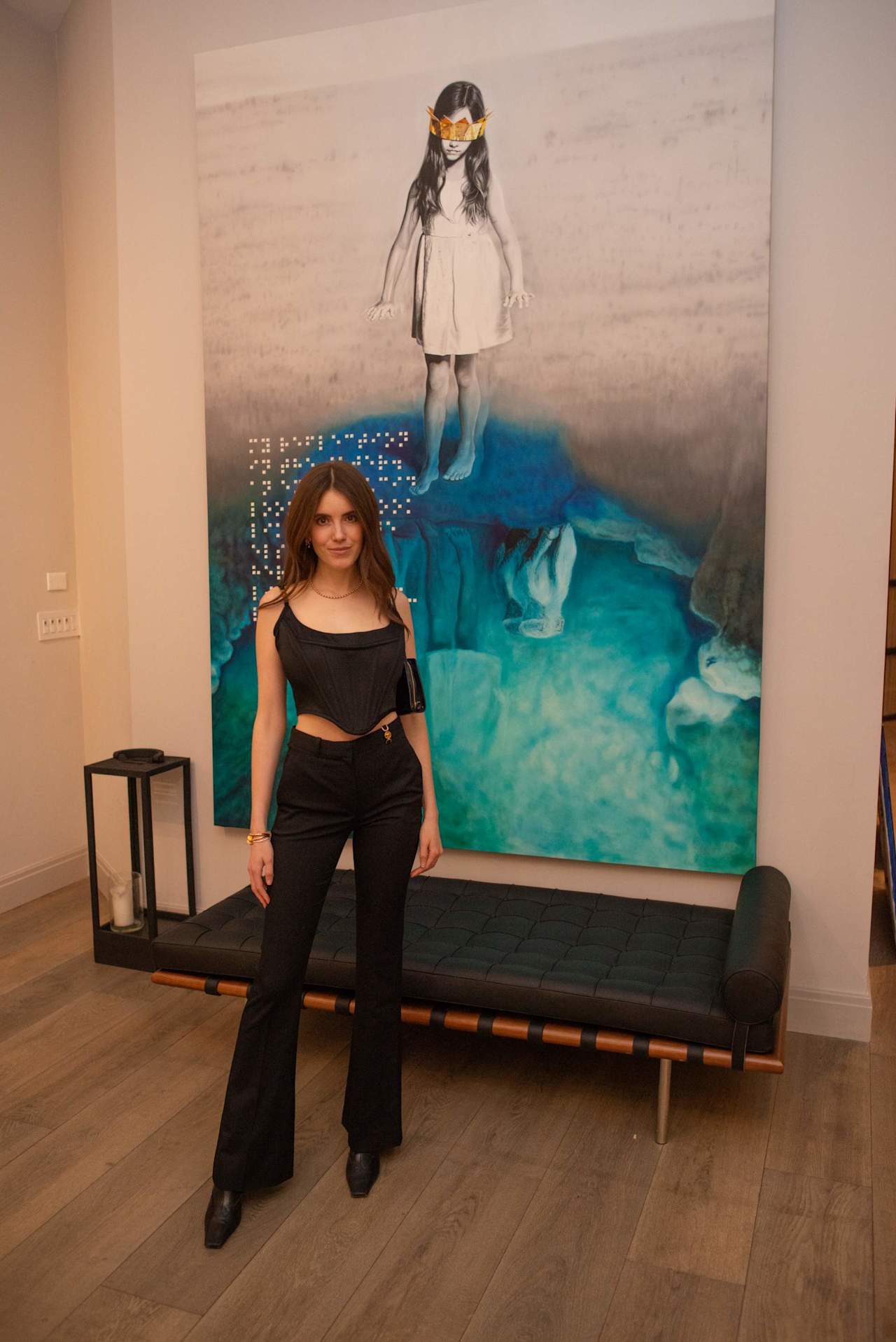 Woman posing in front of a large artwork of a girl above blue water.