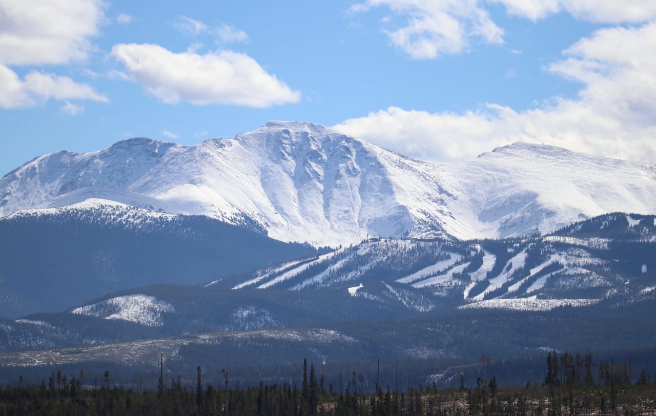 A breathtaking view of a snow-capped mountain surrounded by a lush forest