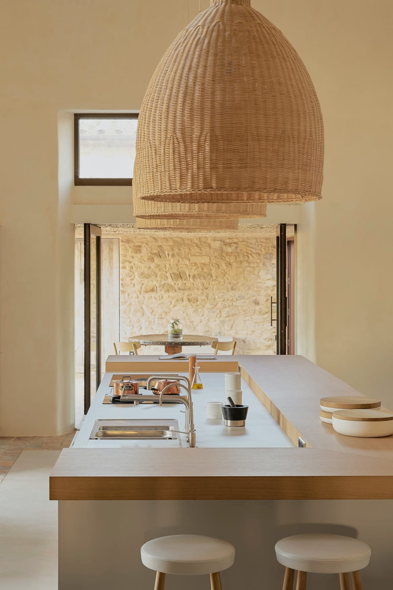 A kitchen with a white quartz island countertop with a wicker pendant lamp hanging from the ceiling.