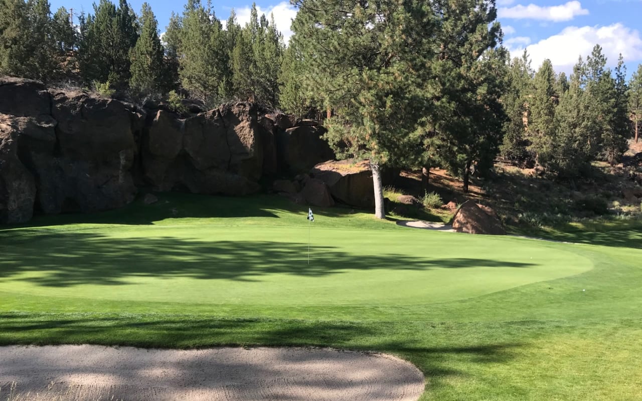 golf hole in a well trimmed grass surrounded by rocks and trees