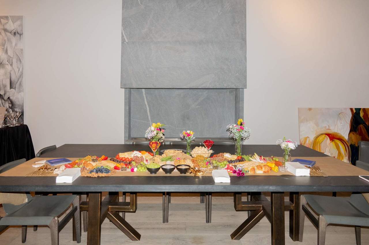 Dining room set for an event with a buffet table, floral arrangements, and a large stone fireplace.