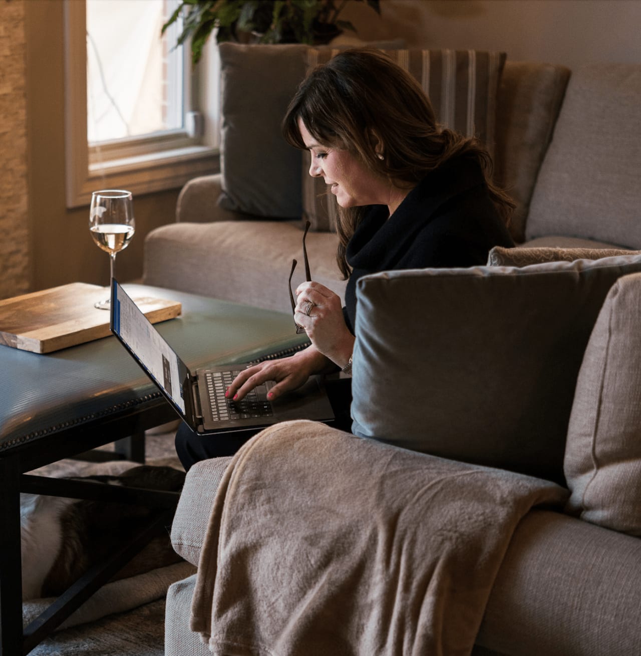 woman sitting on a couch in the living room with laptop tying