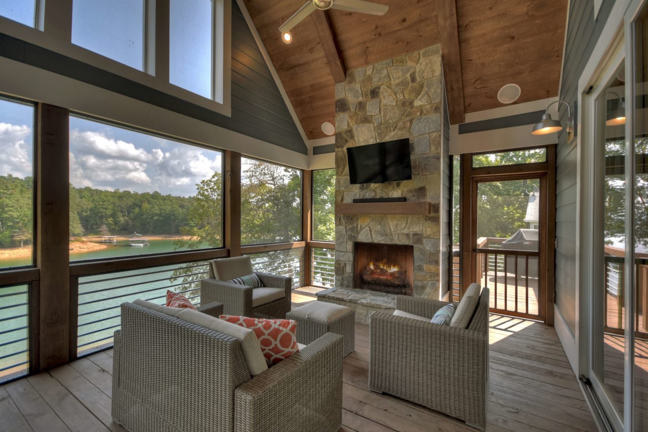 A screened-in porch with a fireplace and wooden furniture.