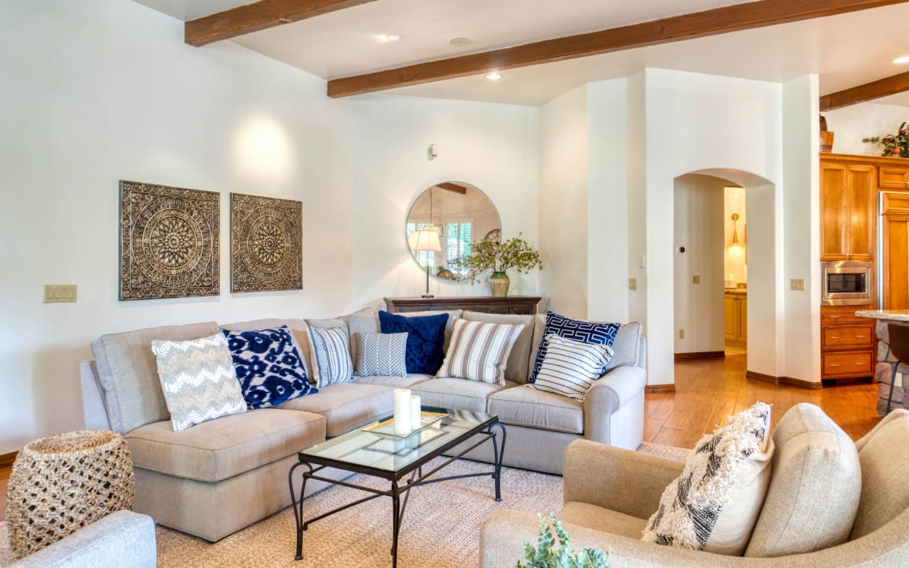 A Mid-century modern living room with a sectional sofa, light hardwood floors, white walls, and a large window on the back.