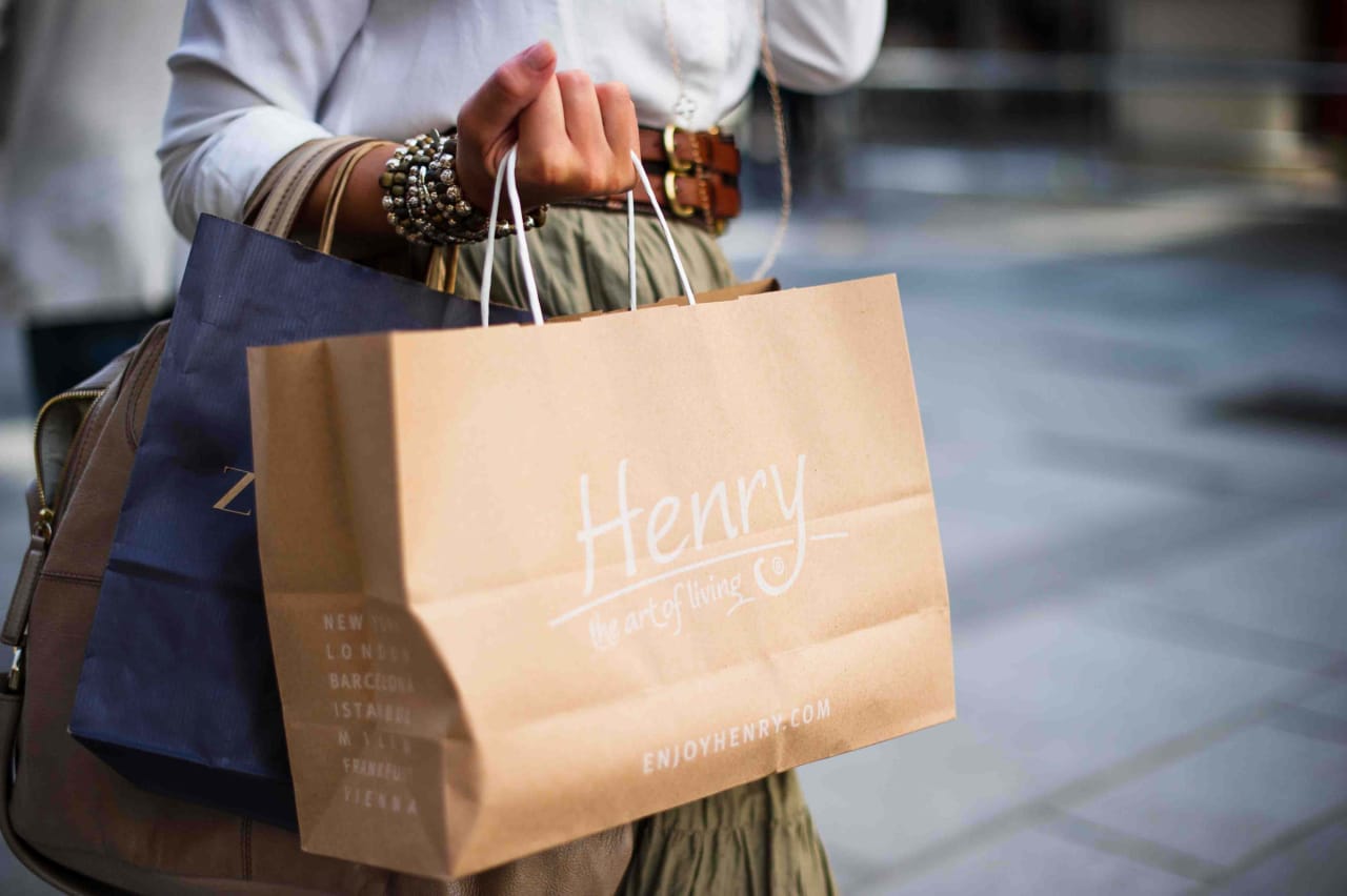 A woman carrying bags from a store called Henry.