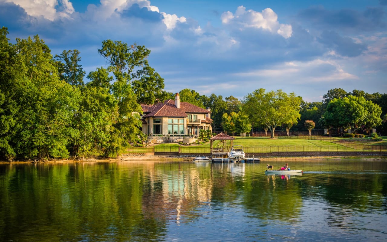 A kayak, canoe, and paddleboard lined up neatly on a wooden dock on a calm lake.