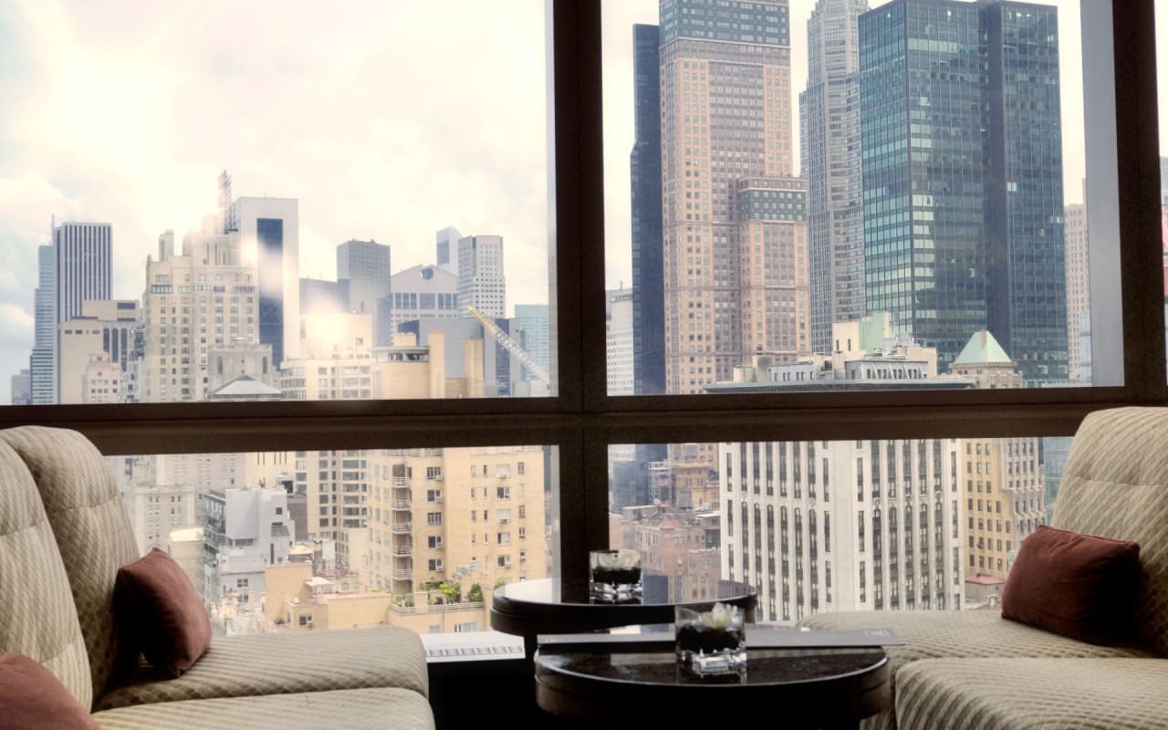 A living room with a view of a city skyline in the morning.