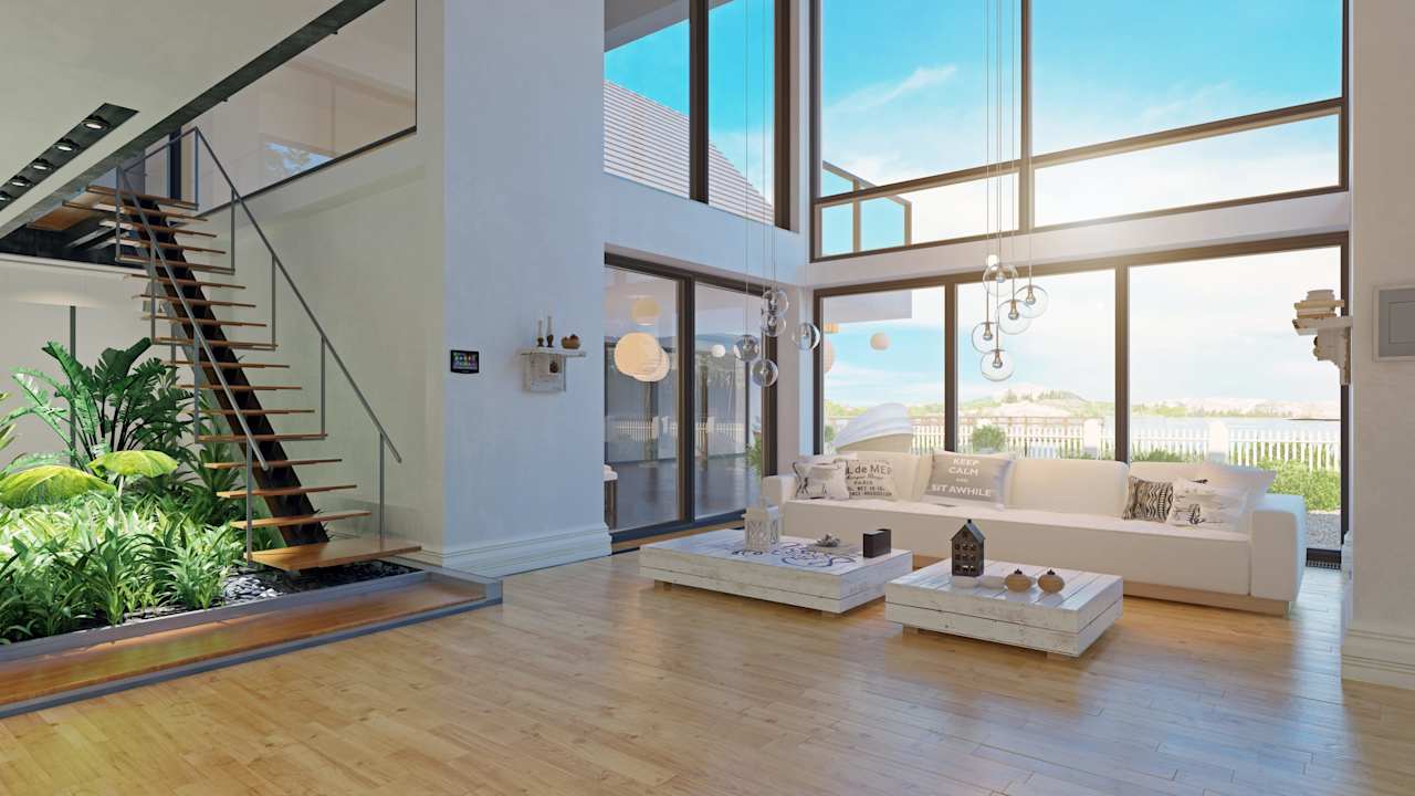 Modern living room with a floating staircase, tall windows, and a white sectional sofa.