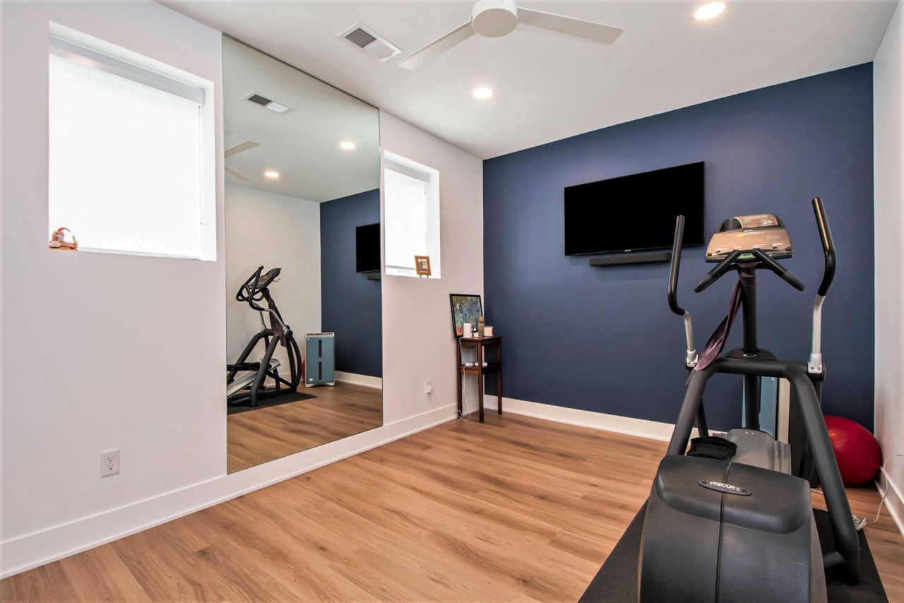 A home gym with a treadmill, elliptical machine, and flat screen TV