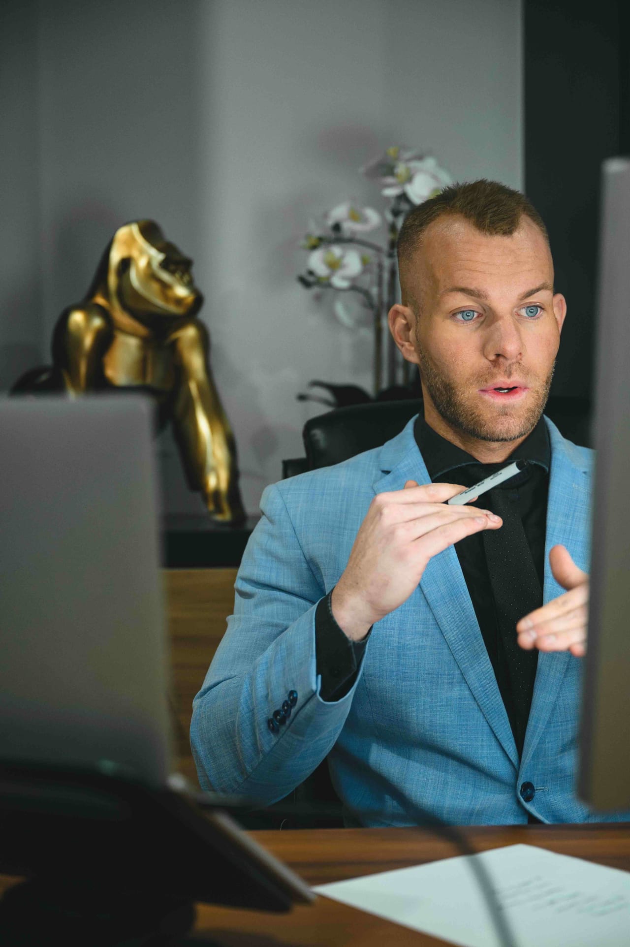 A real estate specialist, Spencer Rivers, attentively discusses offer details during a client negotiation, framed by an elegant office decor.