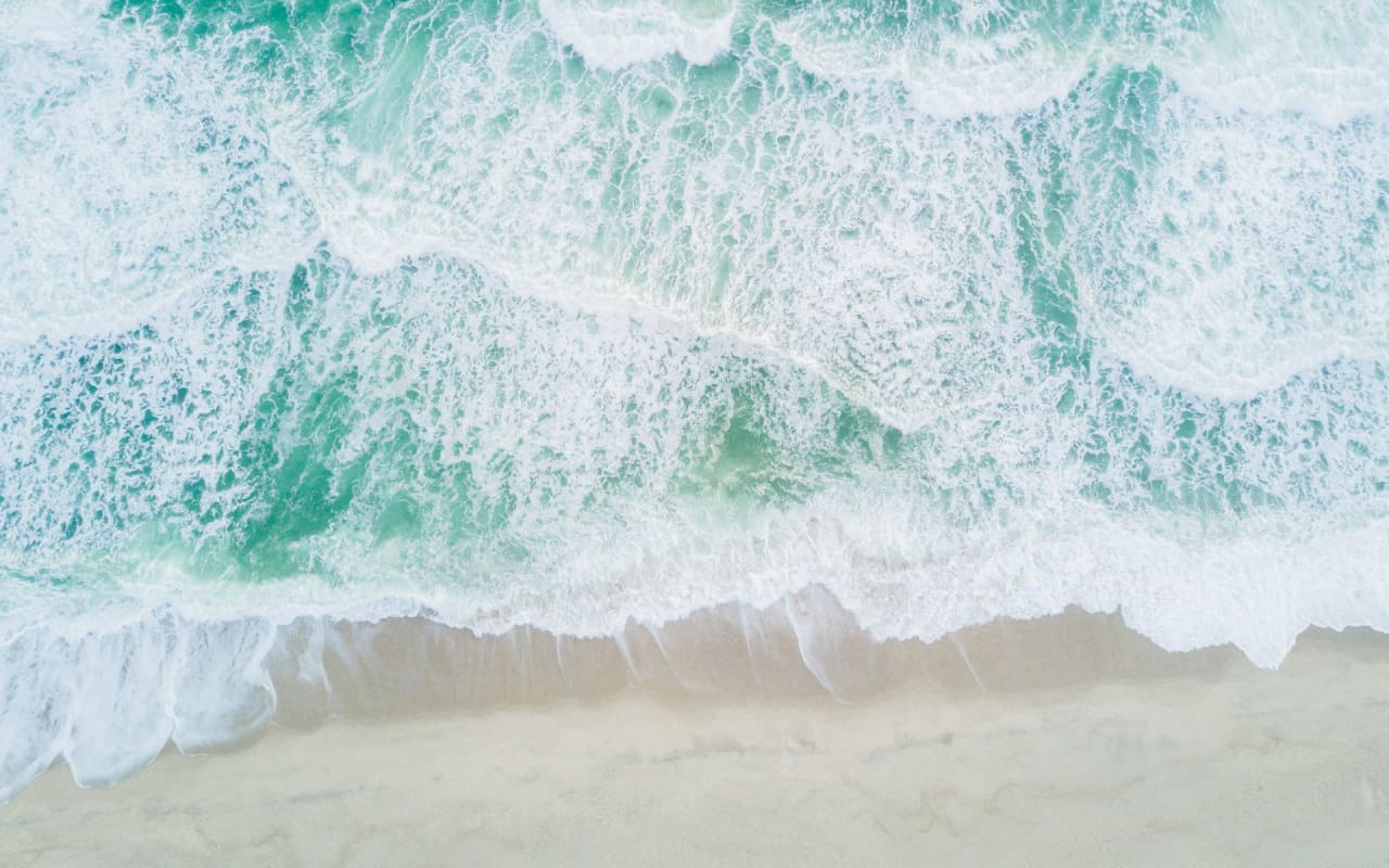 Bright turquoise waves crashing on a sandy beach in Surfside.