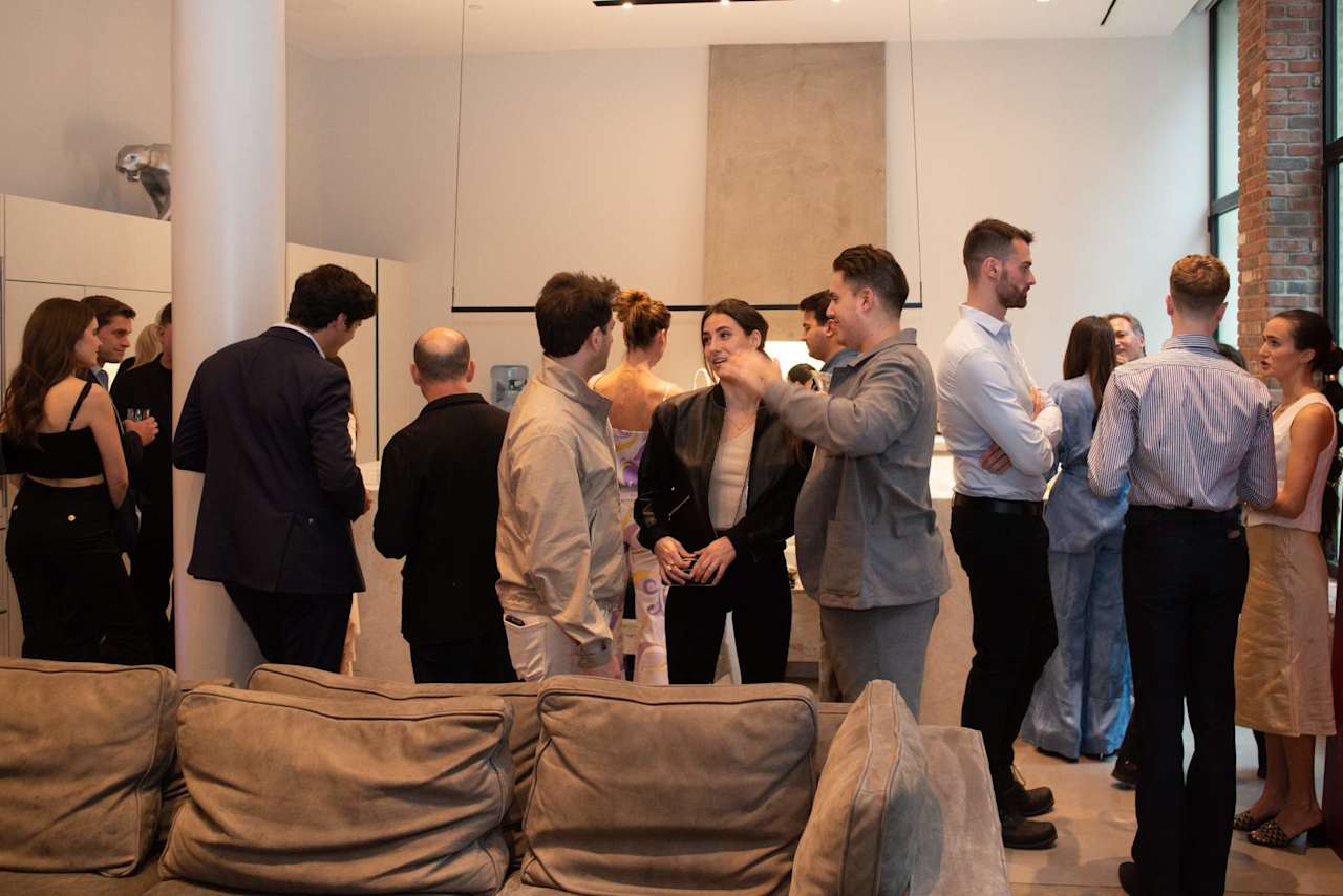 Guests mingle in a modern lounge with sofas in the foreground.