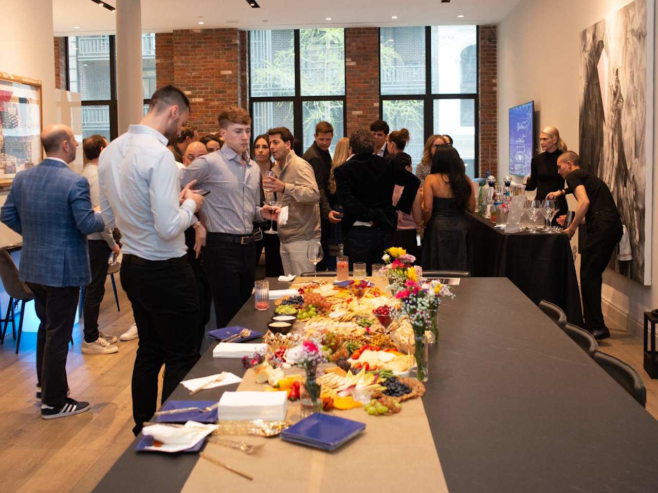 Guests mingle at a networking reception beside a buffet in a brick-walled event space.