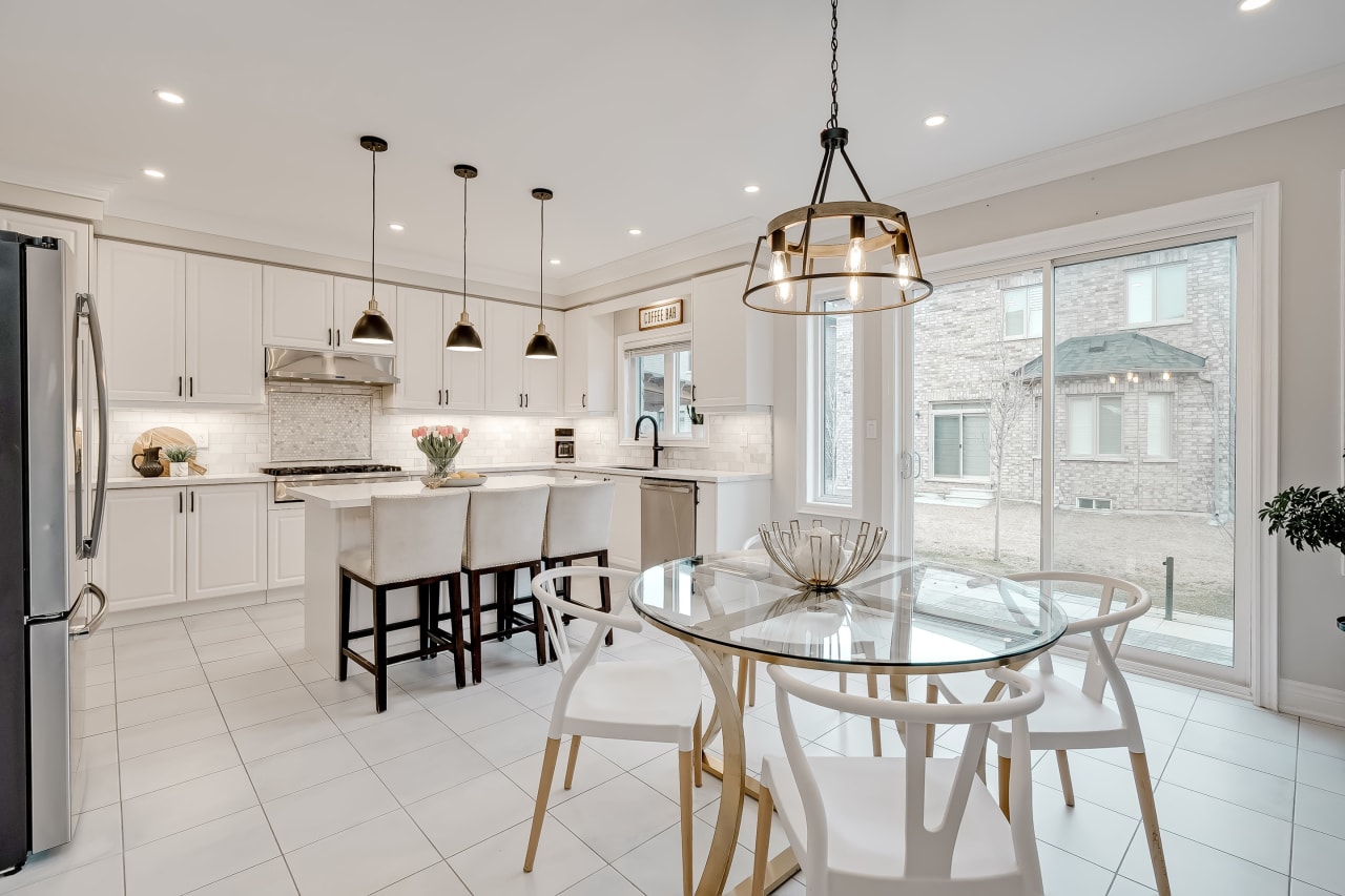 A kitchen with a glass table and four chairs in the center.