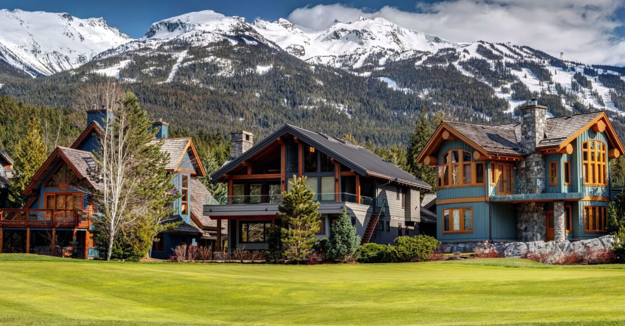 Mountain homes with timber and stone exteriors beneath snow-covered peaks.