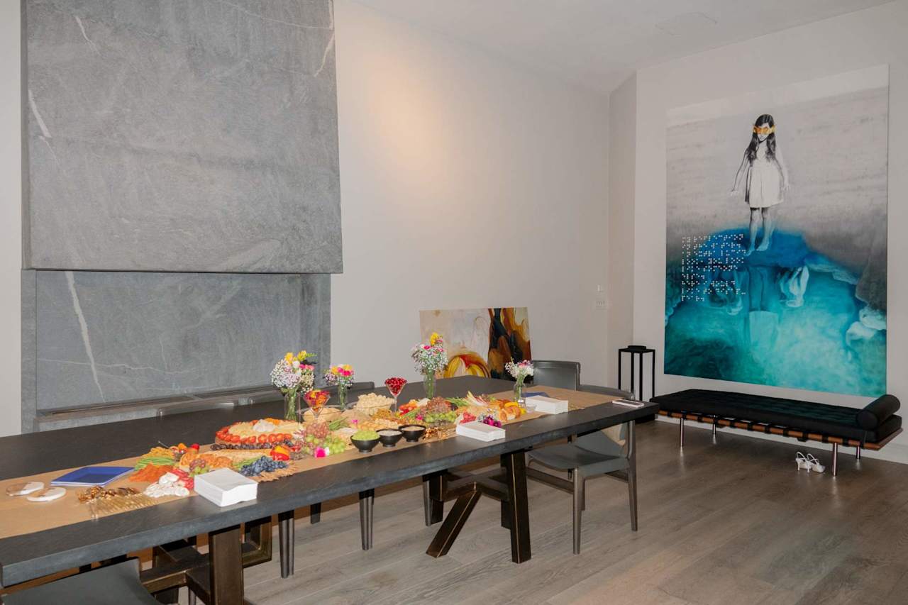 Event dining room with a long buffet table, colorful food, flowers and large artwork.