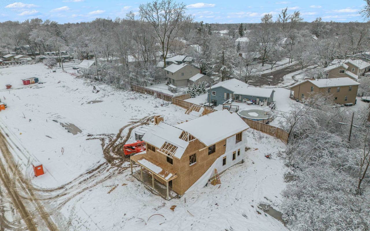 A new house is being built in a snowy neighborhood