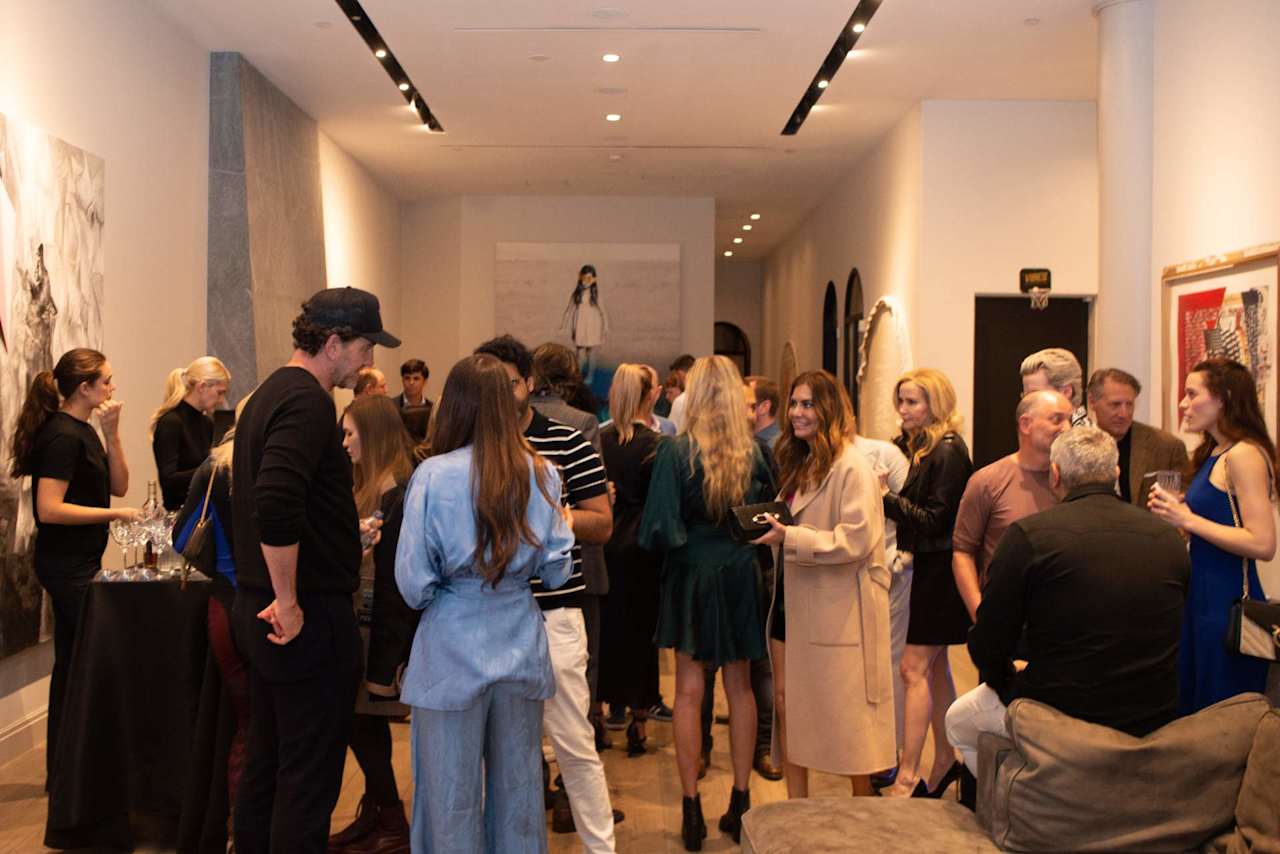 Guests mingle at a reception in a modern gallery-like interior.