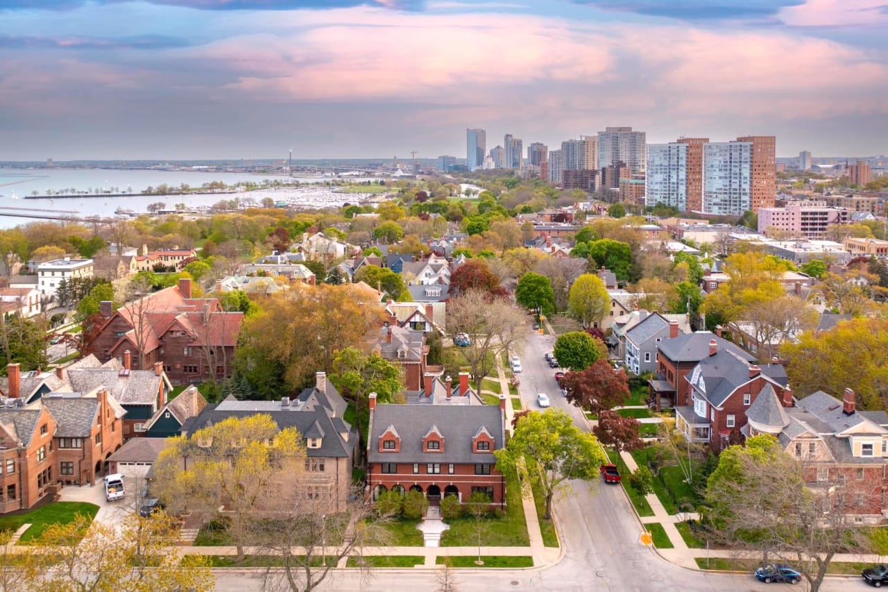 Aerial view of Milwaukee East Side with classic homes, greenery, and Milwaukee skyline near Lake Michigan.