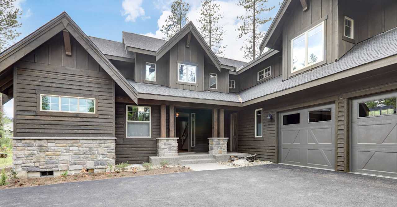 Gray gabled house with stone accents, a covered entry, and an attached two-door garage.